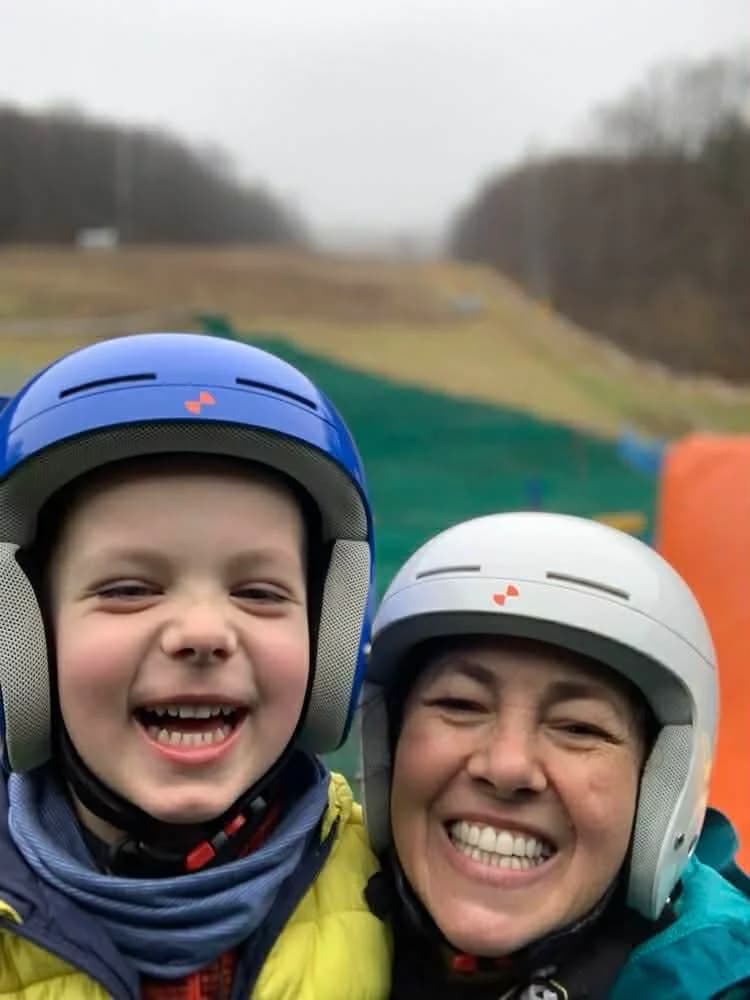 Glückliches Kind und Elternteil nach dem Skikurs